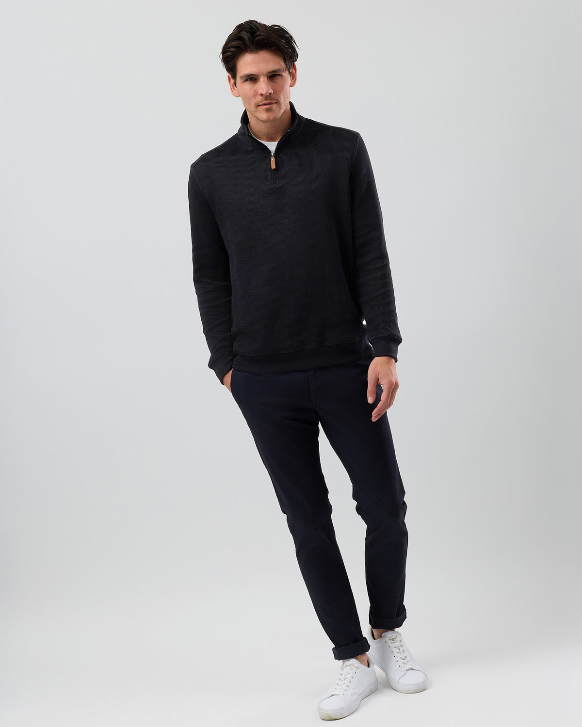 Men's black half zip jumper styled with navy chinos and white sneakers, showcasing the fit of this cotton-rich quarter zip sweater for smart casual wear.