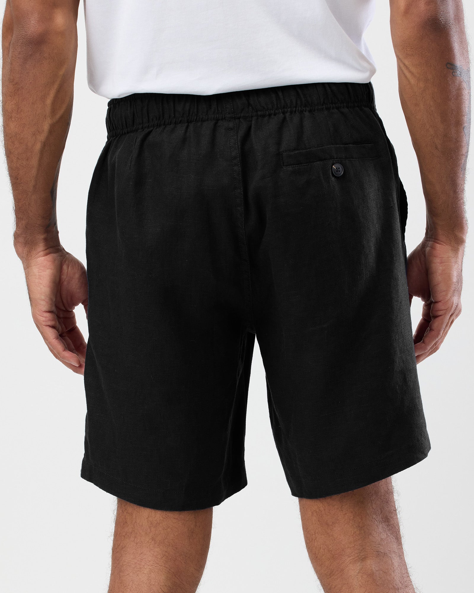 Men's black linen shorts back view with elastic waist and buttoned back pocket