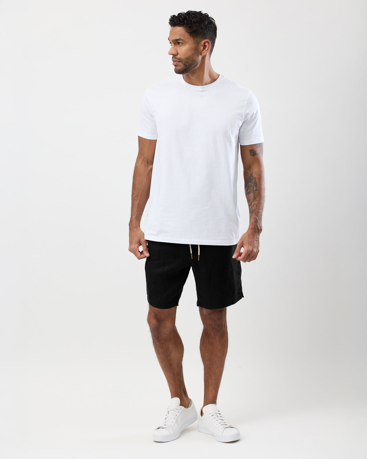 Men's black linen shorts worn with a white T-shirt showing the relaxed fit