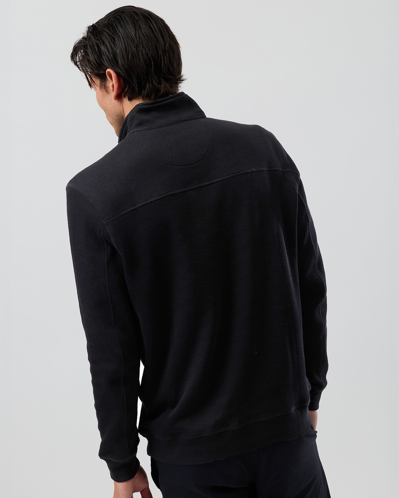 Back view of men's black quarter zip cotton jumper, showing the textured French rib fabric, shoulder stitching, ribbed cuffs and waistband.
