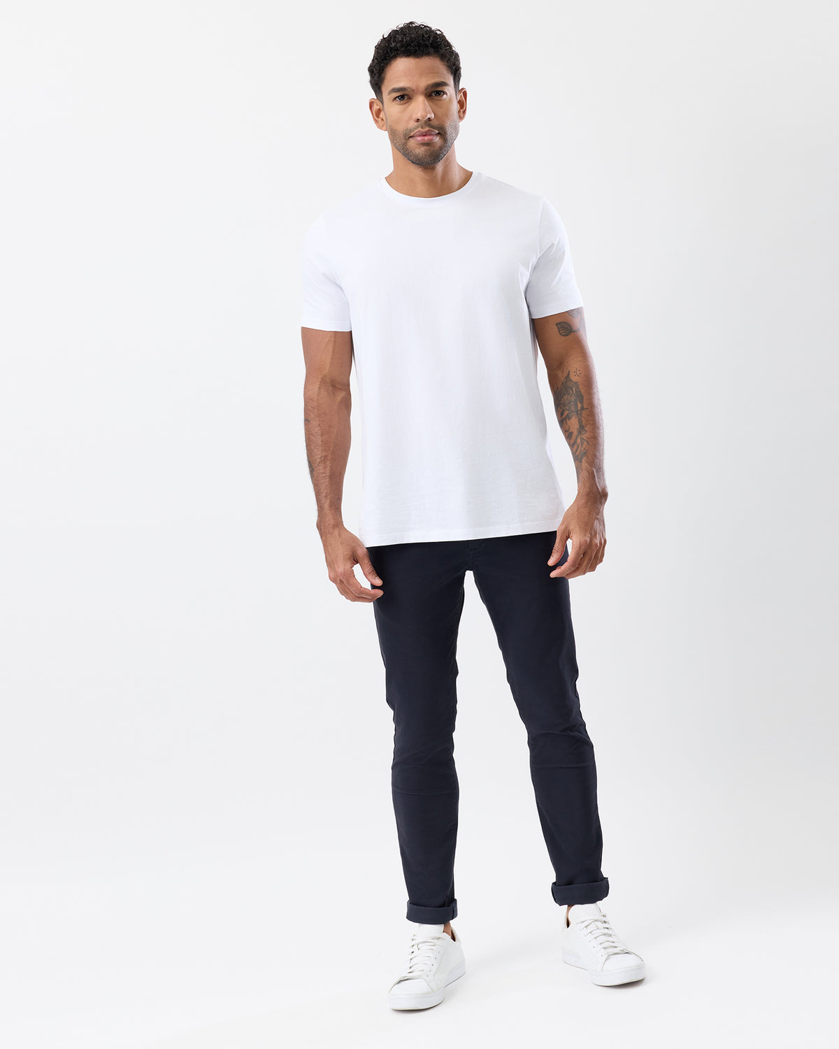 Men's navy slim stretch chinos by Wayver Originals, styled with a white crew neck t-shirt and sneakers, featuring a tapered leg and rolled cuffs.