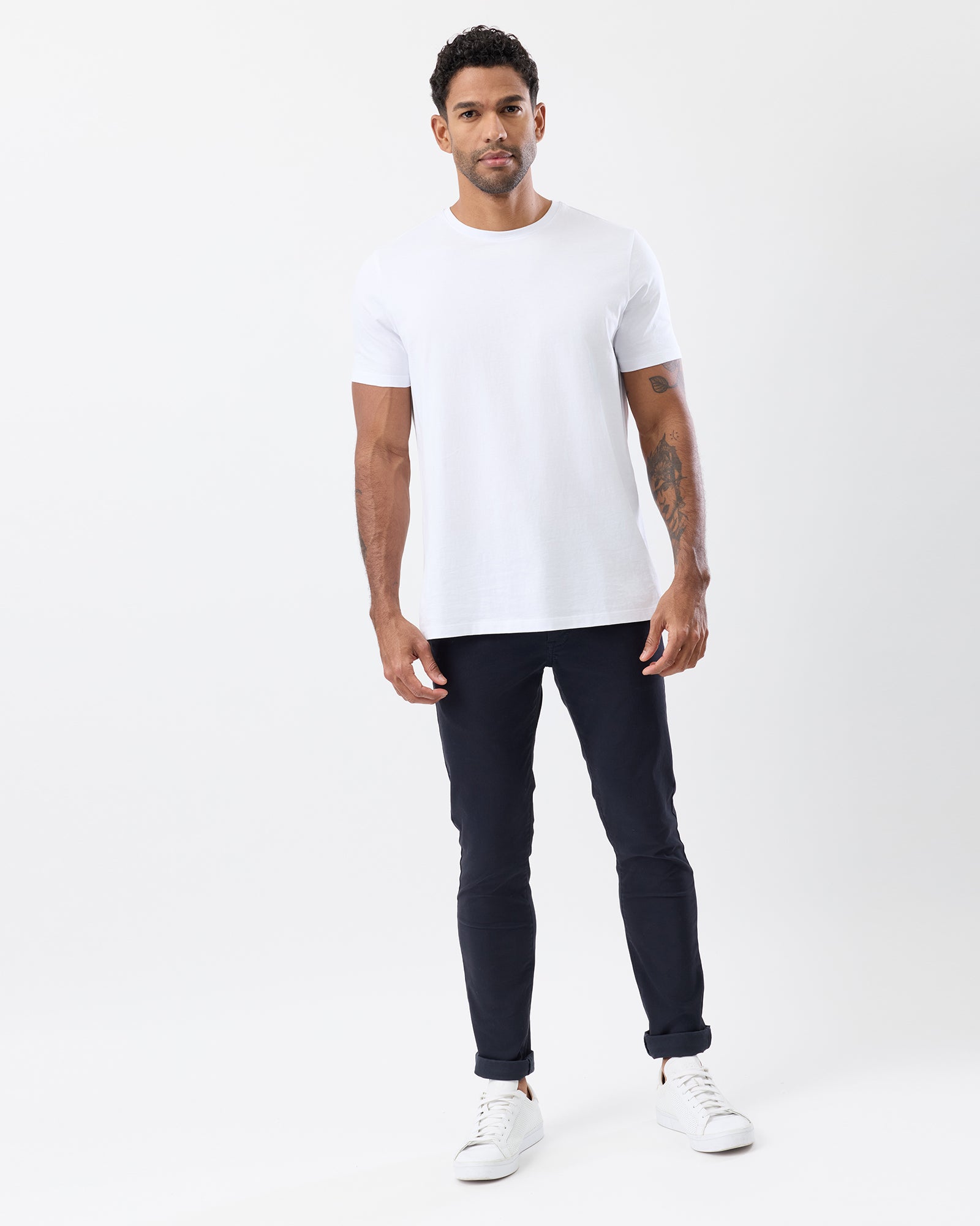Men's navy slim stretch chinos by Wayver Originals, styled with a white crew neck t-shirt and sneakers, featuring a tapered leg and rolled cuffs.