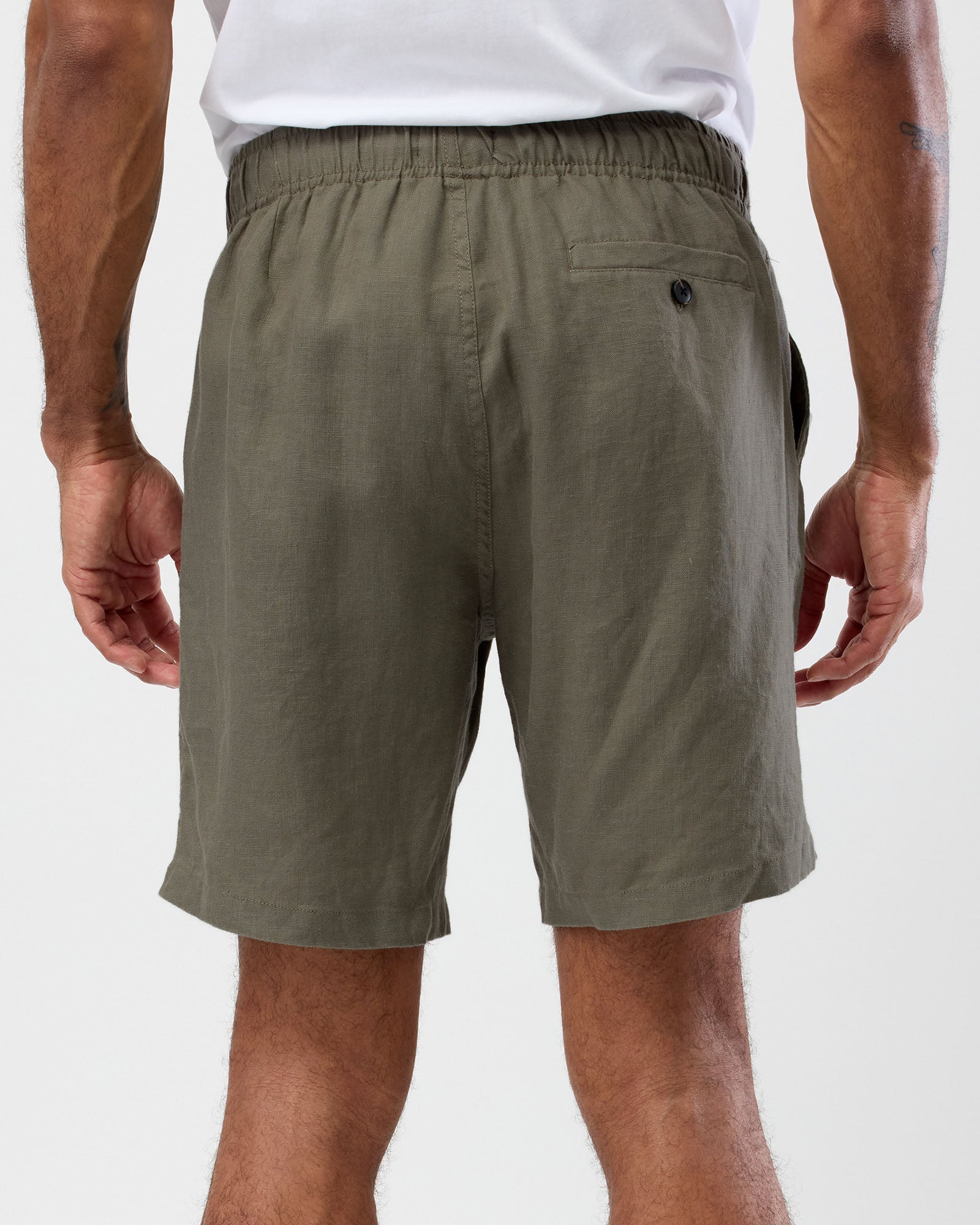 Men's olive linen shorts back view with elastic waist and buttoned back pocket, by wayver originals