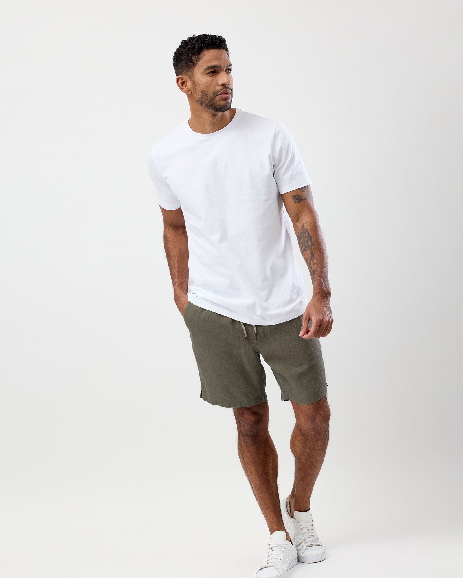 Men's olive linen shorts worn with a white T-shirt showing the relaxed fit