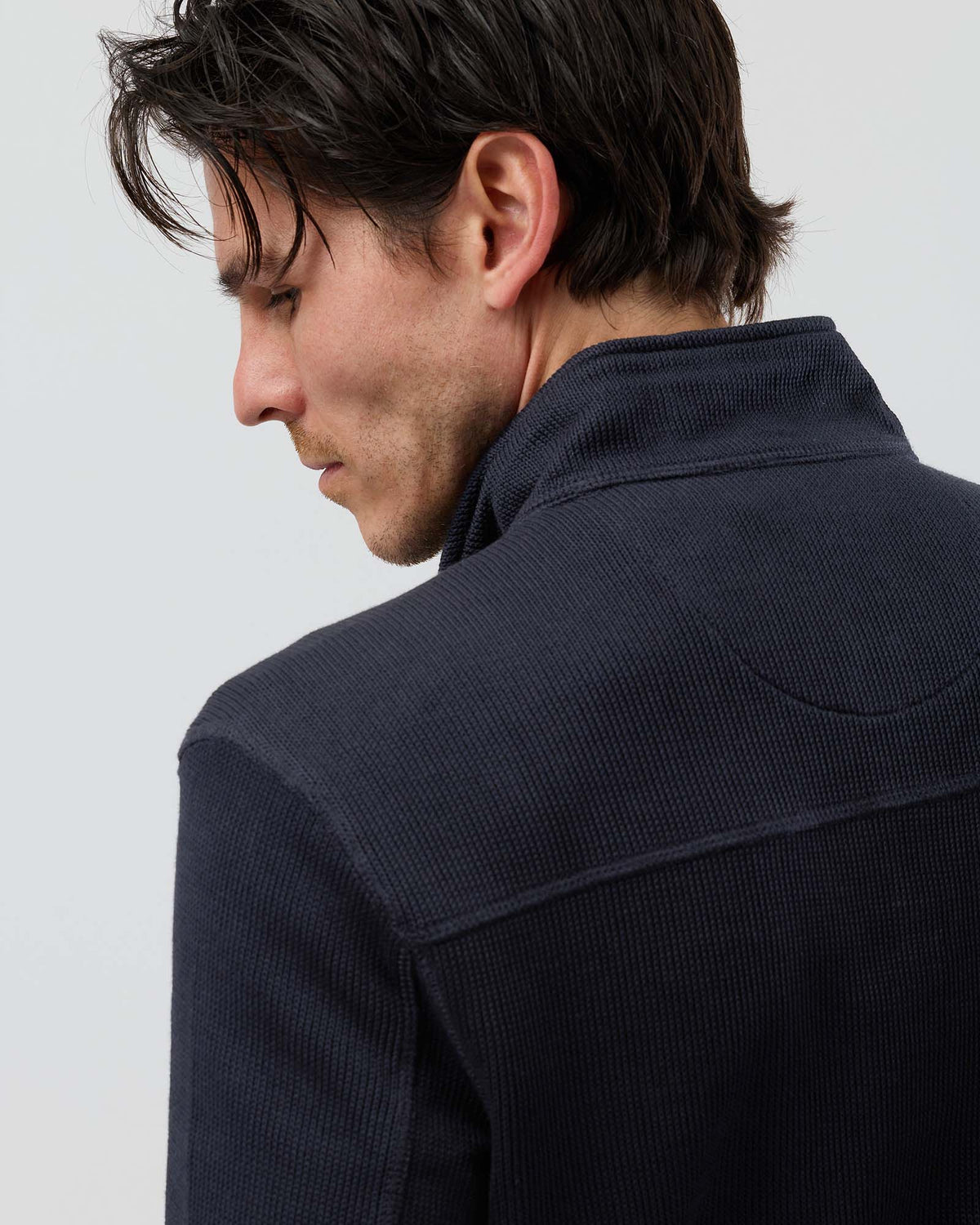 Close-up of navy French rib half zip knit jumper showing textured fabric, shoulder seam construction, back yoke stitching and ribbed collar.