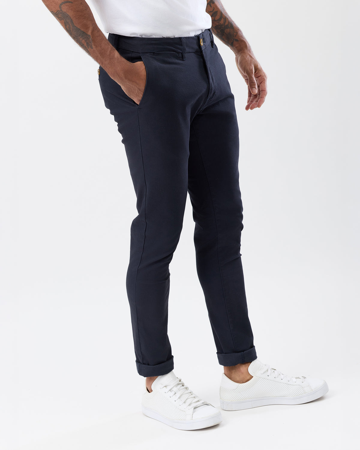 Angled view of men's navy stretch chino pants highlighting the slim tapered silhouette, side pockets and rolled cuffs.