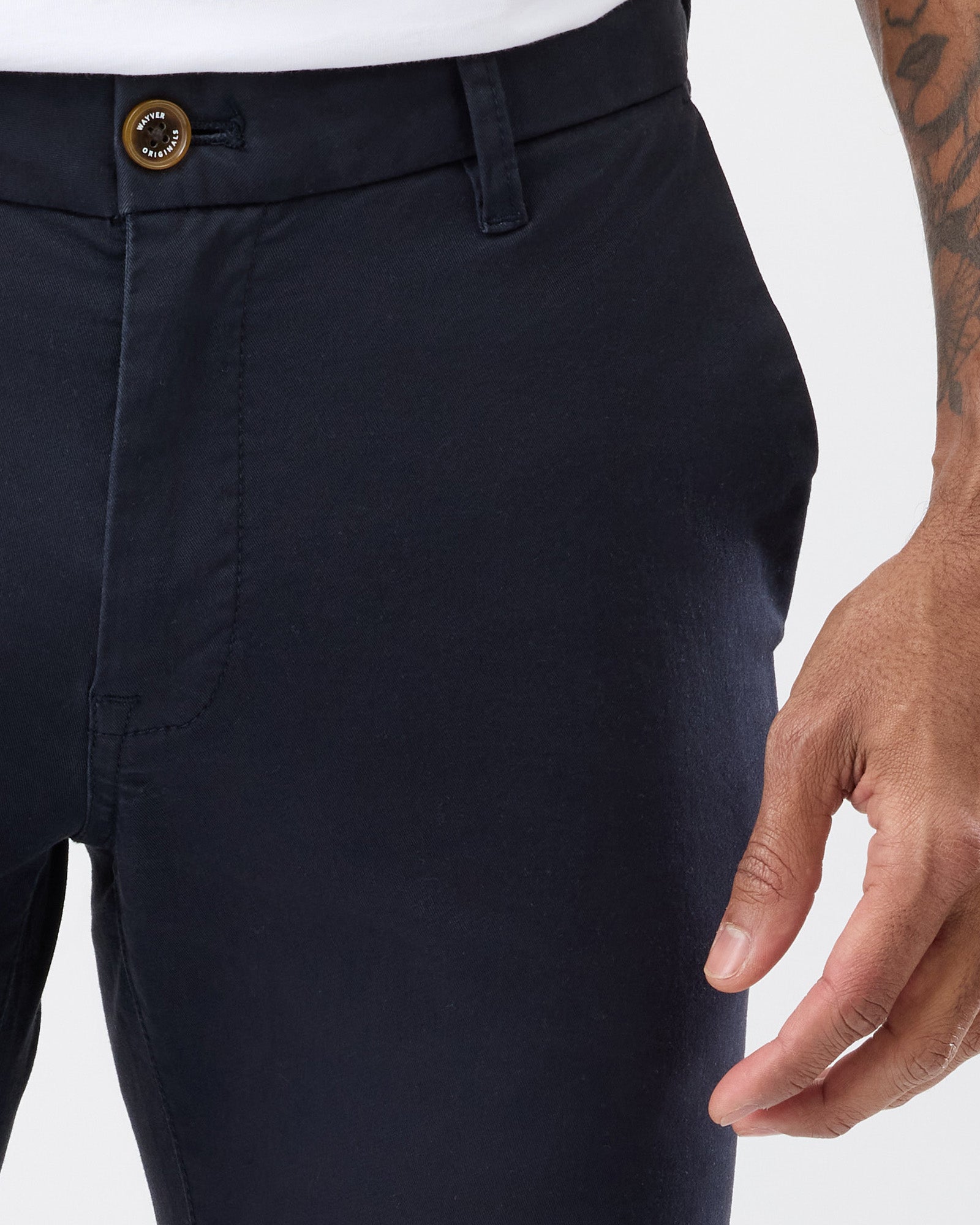 Close-up of Wayver Originals navy stretch cotton chinos showing the branded button, belt loops, front pocket and soft cotton twill fabric.