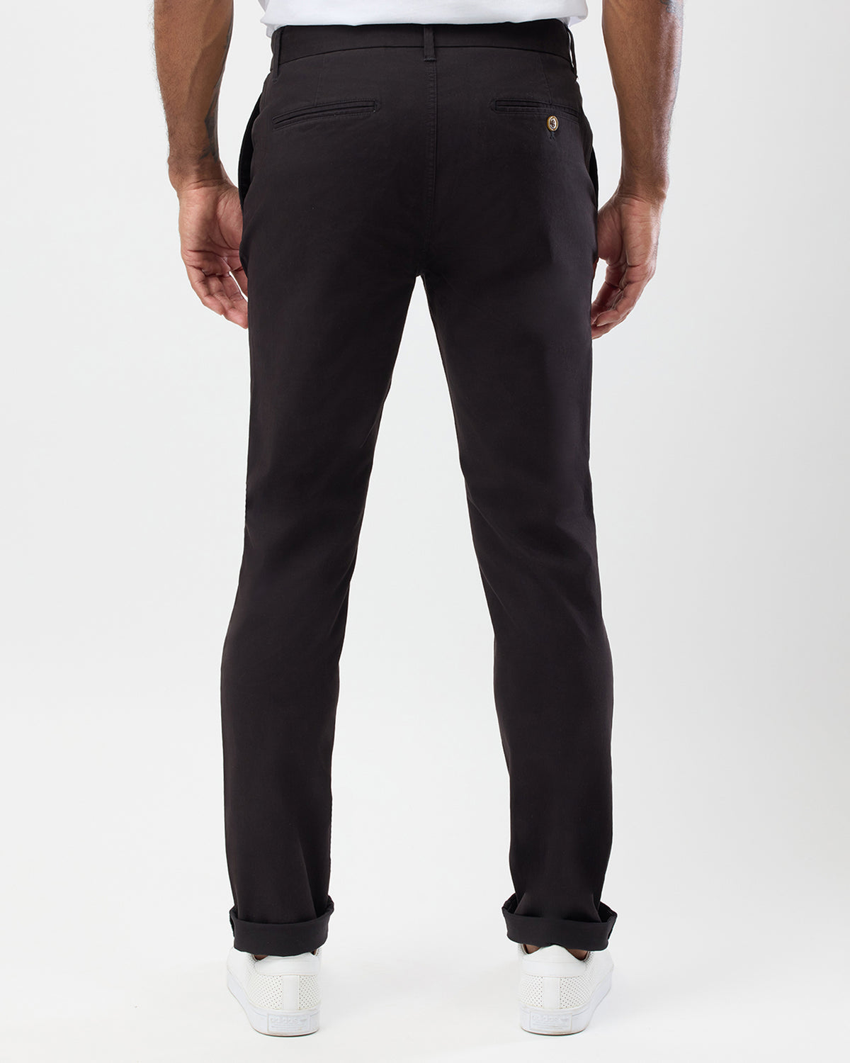Rear view of men's black slim stretch chinos by Wayver Originals showing back welt pockets, button detail and slim tapered fit.