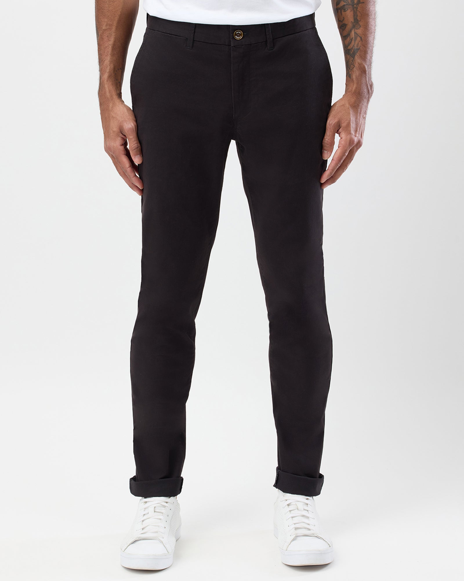 Front view of men's black slim stretch chinos by Wayver Originals, featuring tapered legs and rolled cuffs with white sneakers.