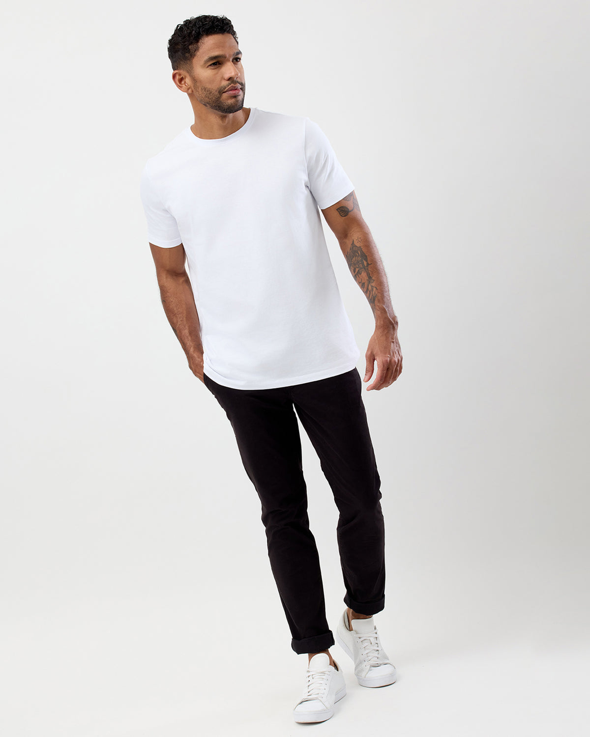 Male model wearing Wayver Originals black slim stretch chinos styled with a white crew neck t-shirt and white sneakers.