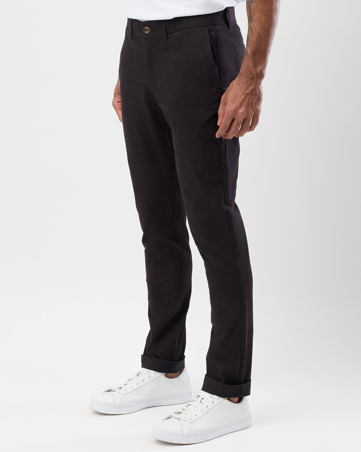Three-quarter side view of Wayver Originals black slim fit chino pants showing side pockets, tapered leg and rolled cuffs.
