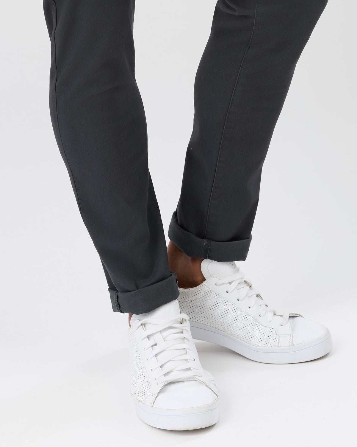 Close-up of men's charcoal slim stretch chinos with rolled cuffs showing the tapered leg fit.