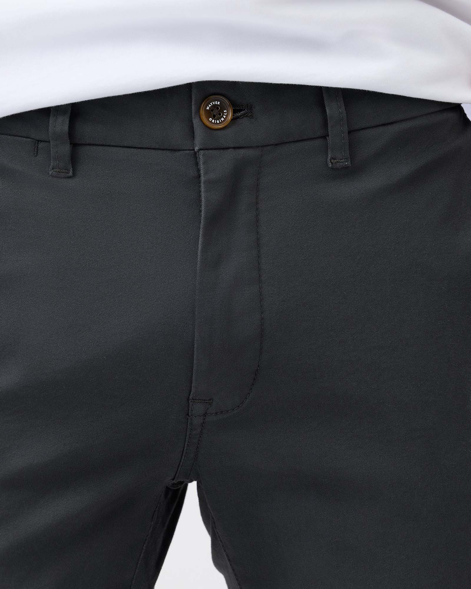Close-up of charcoal chino pants showing waistband, button fastening and front pockets