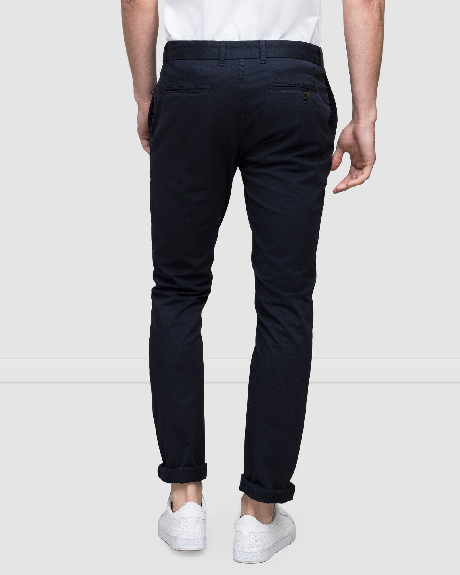 Rear view of men's navy slim fit chinos with rear jet pockets, worn with sneakers 
