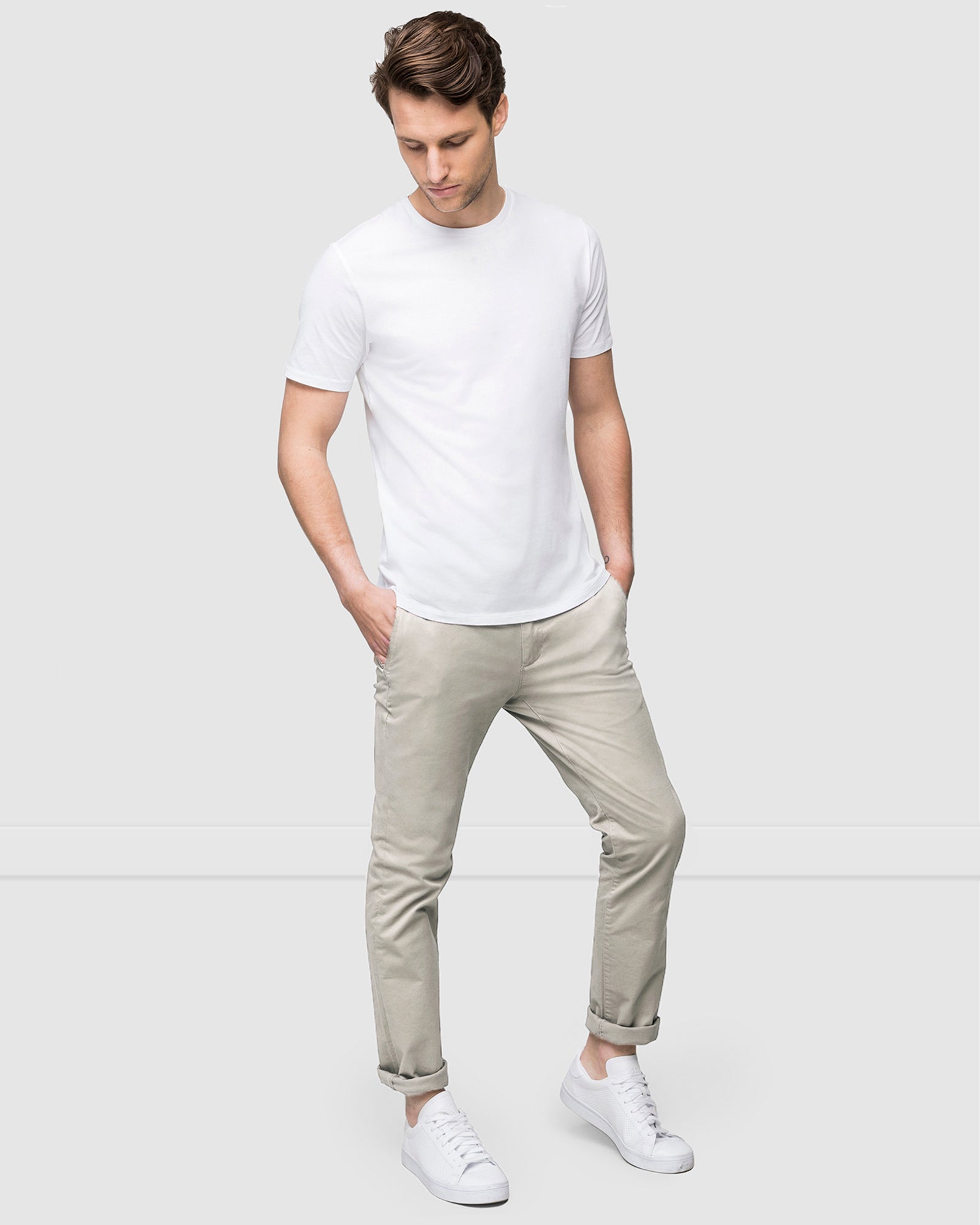 Full body view of model wearing pebble chino pants with white t-shirt and sneakers